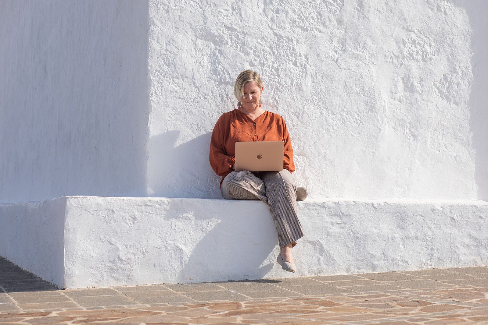 Dr. Mandy Zimmermann trabajando con el portátil junto a un muro blanco en Fuerteventura